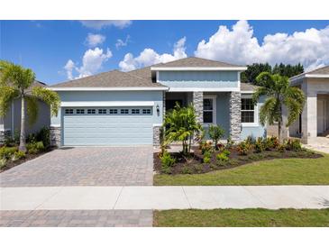 Curb appeal abounds in this charming house featuring a light blue exterior, gray stone accents and lush landscaping at 1017 Signet Dr, Apollo Beach, FL 33572