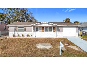 Newly renovated single-story home with a gray exterior, white garage door, and landscaped lawn at 6941 Twilite Dr, Port Richey, FL 34668