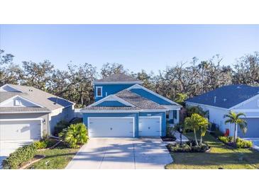 Two-story house with blue siding, two-car garage, and landscaping at 3514 Shimmering Oaks Dr, Parrish, FL 34219