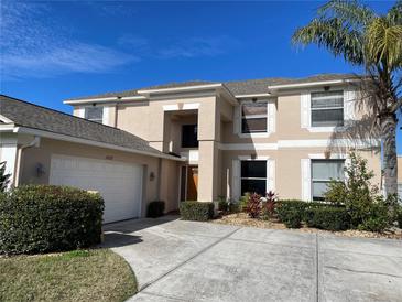 Two-story house with beige exterior, white garage door, and landscaping at 25737 Frith St, Land O Lakes, FL 34639