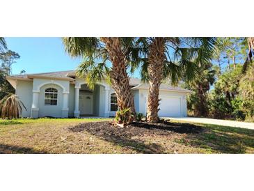 Newly constructed home with light gray exterior, two palm trees, and a spacious yard at 2559 Comet Ln, North Port, FL 34286