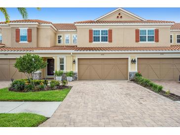 Tan three-story townhome with two-car garage and landscaped front yard at 8726 Terracina Lake Dr, Tampa, FL 33625