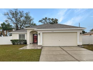 One-story home with a red door, attached garage, and landscaped yard at 1502 Silktree Ct, Brandon, FL 33511