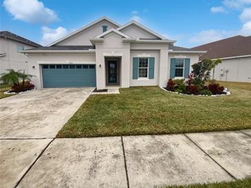 Single-story house with teal garage door and landscaped lawn at 4739 Butler National Dr, Wesley Chapel, FL 33543