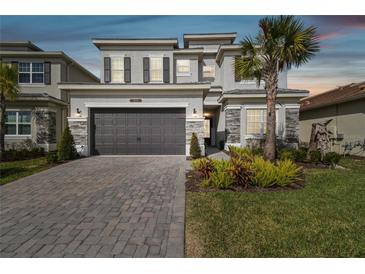 Two-story house with gray siding, stone accents, and a 3-car garage at 3135 Great Banyan Way, Wesley Chapel, FL 33543