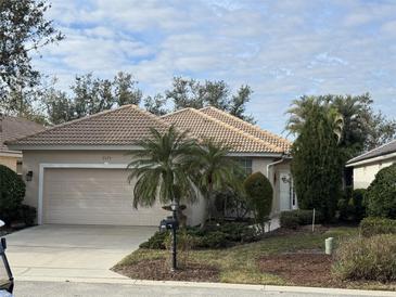 Tan single-story house with a two-car garage and palm trees at 3375 Osprey Ln, Port Charlotte, FL 33953