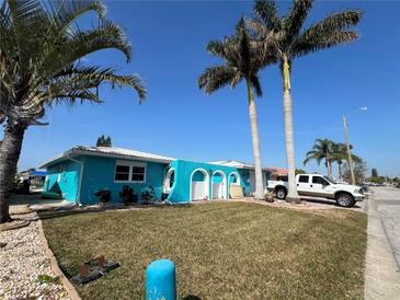 Bright teal house with palm trees, lush lawn, and a paved driveway at 4903 Shell Stream Blvd, New Port Richey, FL 34652