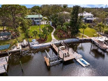 Waterfront home featuring a boat dock, lush landscaping, and charming two-story home at 3225 Bluff Blvd, Holiday, FL 34691