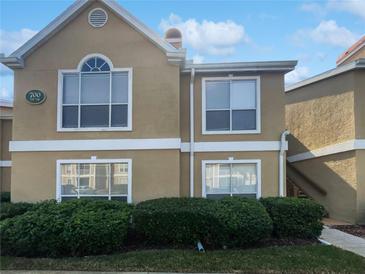 Two-story tan condo building with white trim, green bushes, and blue skies at 9481 Highland Oak Dr # 703, Tampa, FL 33647