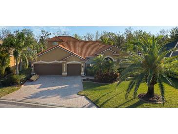 Stunning tile roof with an elegant tan exterior, spacious three car garage, and lush landscaping at 6977 74Th Street E Cir, Bradenton, FL 34203