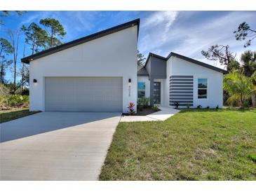 Modern home with a stylish gray and white exterior, two-car garage, and freshly installed landscaping at 4044 Simkins Ave, North Port, FL 34286