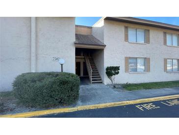 Condo exterior featuring a stucco facade, staircase, and well-maintained landscaping at 7502 Needle Leaf Pl # B66, Tampa, FL 33617