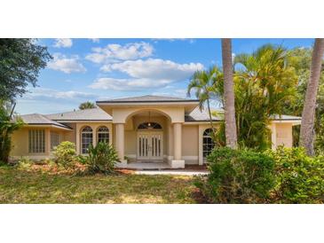 Charming one-story home featuring a manicured front yard, arched entryway, and lush tropical landscaping at 26058 Paysandu Dr, Punta Gorda, FL 33983