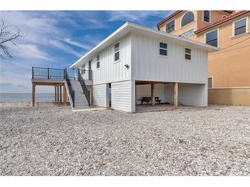 Charming raised beach house featuring stairs to a deck with ocean view and ground level covered parking at 6417 Driftwood Dr, Hudson, FL 34667