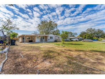 Charming single-story home featuring a spacious front yard under a blue sky with scattered clouds at 5350 47Th N Ave, St Petersburg, FL 33709