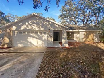 Single-story home featuring an attached two-car garage with a stone accent wall and well-maintained landscaping at 8379 Begonia St, Spring Hill, FL 34608