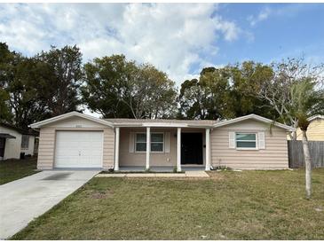 Charming single-story home with a front lawn, attached garage, and covered entryway supported by columns at 4325 Newbury Dr, New Port Richey, FL 34652