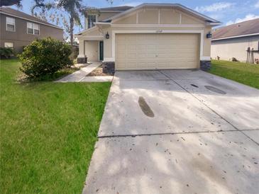 Inviting two-story home showcasing a two-car garage, lush lawn, and well-maintained landscaping at 12549 Chenwood Ave, Hudson, FL 34669