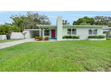 Charming light green house with a pink door and well-manicured lawn at 739 Jasmine Way South, St Petersburg, FL 33705