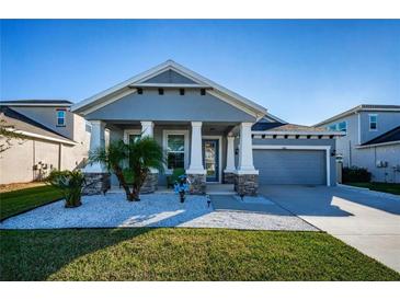 One-story home with gray siding, two-car garage, and landscaped front yard at 1280 Windy Bay Shl, Tarpon Springs, FL 34689