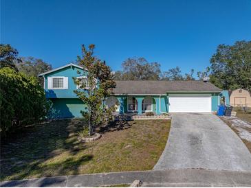 Teal home with a white garage door and arched entryway at 1008 Highgrove Ct, Valrico, FL 33596