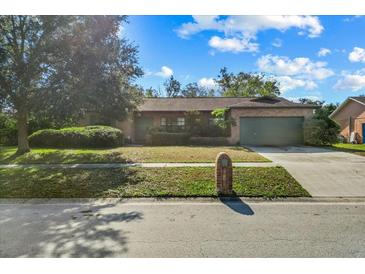 Brick house with a green garage door and well-maintained lawn at 1813 Laurel Oak Dr, Valrico, FL 33596