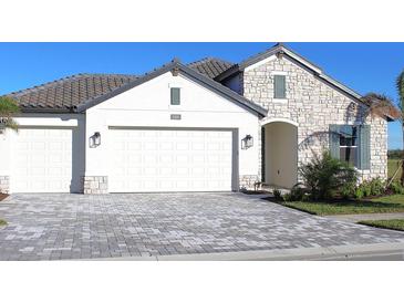 Two-story home with stone accents and a paver driveway at 2004 Bolsena St, Nokomis, FL 34275