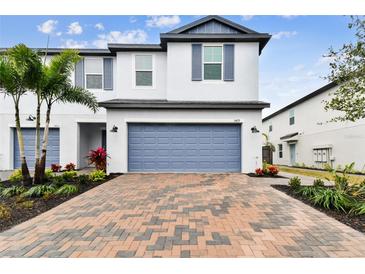 Two-story townhome with a blue garage door and a brick paver driveway at 5429 Tripoli Dr, Palmetto, FL 34221