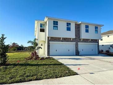 Two-story house with a two-car garage, stone accents, and a neatly landscaped lawn at 13719 Emerald Fields Dr, Hudson, FL 34667