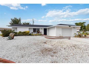 White single story home with a gravel yard, attached garage, and a small deck at 6628 Keystone Dr, Sarasota, FL 34231