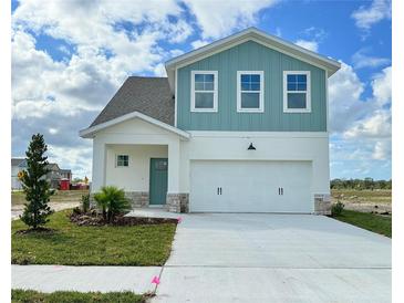 Two-story house with light teal and white siding, three-car garage, and landscaping at 7950 Chandler Lake Ct, Hudson, FL 34667