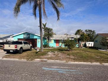 Charming aqua-colored home with well-maintained lawn and tropical landscaping at 246 176Th E Ave, Redington Shores, FL 33708