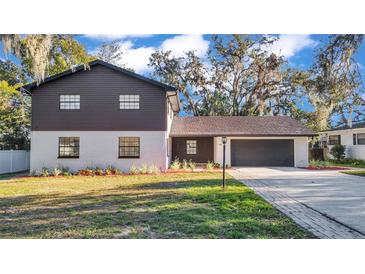 Two-story home with updated exterior, landscaping, and driveway at 407 Belvedere Oval, Temple Terrace, FL 33617