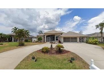 House exterior features a large driveway and manicured lawn at 13 Pebble Beach Rd, Rotonda West, FL 33947