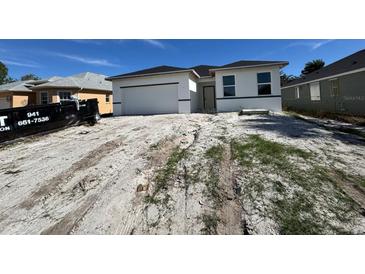 Newly constructed one-story home featuring an attached two-car garage, clean lines, and modern design at 104 Australian Dr, Rotonda West, FL 33947