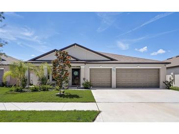 Single-story house with three-car garage, landscaping, and a neutral color scheme at 288 Rain Berry Ave, Ruskin, FL 33570