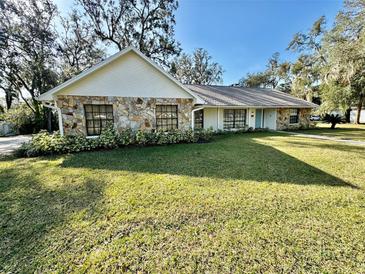 Ranch style home with stone facade, spacious lawn, and mature trees at 1501 Buell Ct, Plant City, FL 33567