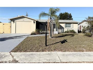 Ranch-style home with attached garage and a well-maintained lawn at 3615 Wellington Dr, Holiday, FL 34691