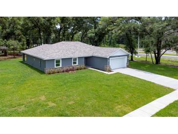 Single-story home with gray siding, stone accents, and a two-car garage at 11734 Orange Ct, Dade City, FL 33525