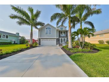 Two-story house with gray siding, stone accents, and a two-car garage,palm trees and landscaping at 4334 Sanddollar Ct, New Port Richey, FL 34652