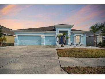 Cute light blue house with a two-car garage and manicured lawn at 6843 Boulder Run Loop, Wesley Chapel, FL 33545