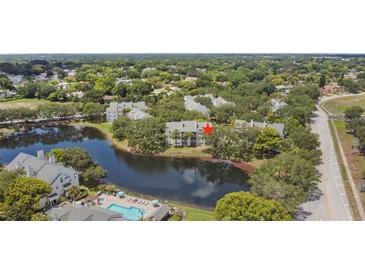 Aerial view of condo community near lake with pool and lush landscaping at 3265 Haviland Ct # 302, Palm Harbor, FL 34684