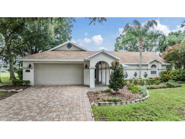 House exterior featuring a paved driveway, attached garage, and nicely landscaped yard at 6132 Silver Oaks Dr, Zephyrhills, FL 33542