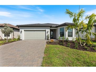 Single-story home with gray siding, paver driveway, and landscaped lawn at 1877 Pepper Grass Dr, North Port, FL 34289