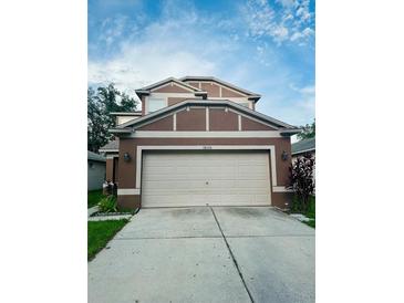 Two-story home featuring a two-car garage, concrete driveway, and well-maintained landscaping at 18135 Canal Pointe St, Tampa, FL 33647