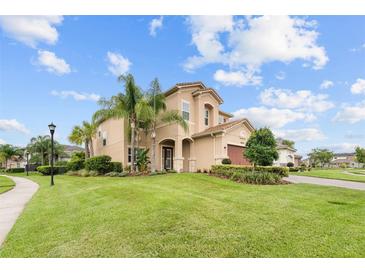 Two-story house with tan exterior, palm trees, and manicured lawn at 30723 Lindentree Dr, Wesley Chapel, FL 33543