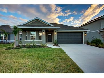 One-story home with gray siding, dark gray garage door, and landscaped lawn at 16115 69Th Lane E Pl, Parrish, FL 34219