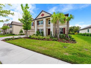 Charming two-story home with a beautifully landscaped yard, lush greenery, and fresh green grass at 33346 Kateland Dr, Wesley Chapel, FL 33545