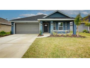 Charming one-story home with gray garage door and manicured lawn at 7018 162Nd E Pl, Parrish, FL 34219