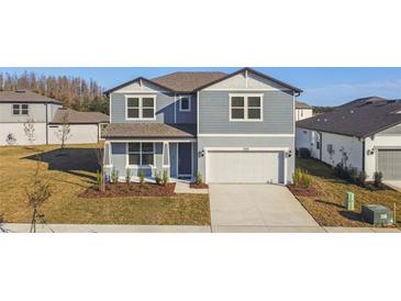 Two-story house with gray siding, white garage door, and landscaped lawn at 1268 Kazaz Ct, Zephyrhills, FL 33540